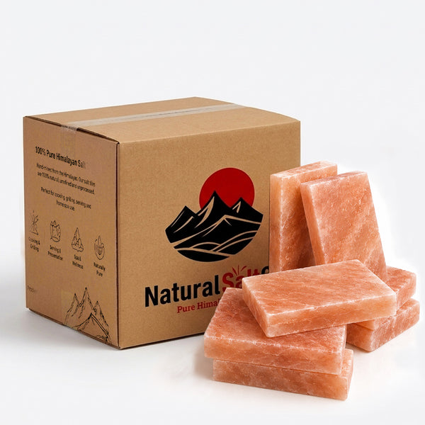 A brown cardboard box labeled Natural Salt Pure Himalayan Salt with a red sun and black mountain logo, shown next to several pink Himalayan salt blocks on a white background.