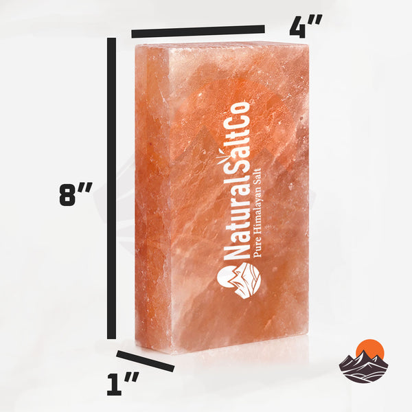A rectangular Himalayan salt block with dimension labels showing 8 inches tall, 4 inches wide, and 1 inch thick, on a white background. The block is orange-pink with white printed text reading 'Natural SaltCo' and 'Pure Himalayan Salt.