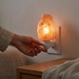 Person turning on a warm glow night light on a wall socket.